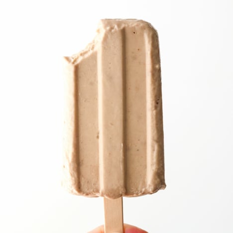 banana popsicle held up with a bite taken out of it.