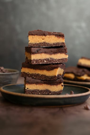 chocolate peanut butter bars stacked on dark plate.
