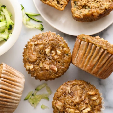 healthy zucchini muffins on a marble surface near shredded zucchini.
